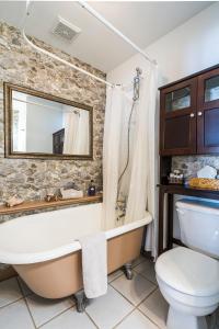 baño con pared de piedra, bañera y aseo en The Inn on Bay, en Gravenhurst