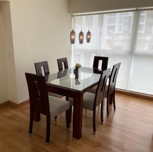 a dining room table with black chairs and a table and a light at Miraflores 2 Bedrooms Executive Apartment in Lima