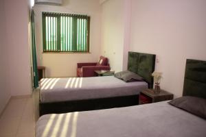 una habitación de hotel con 2 camas y una silla en Apex rest house en Ereván