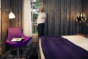 a man talking on a cell phone in a hotel room at Mercure Salzburg City in Salzburg