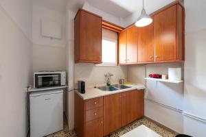 una piccola cucina con armadi in legno e lavandino di Διαμέρισμα 55 τ.μ. στο κέντρο με δωρεάν πάρκινγκ a Larisa