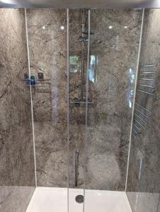 a shower with a glass door in a bathroom at Red darren luxury hut in Llanveynoe