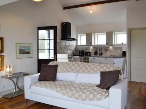 a living room with a white couch and a kitchen at Plas Bach in Llanon