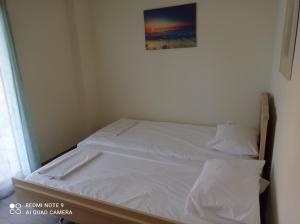 a bed with white sheets and a picture on the wall at Sunset Apartment in Epanomi