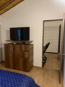a bedroom with a tv on top of a wooden dresser at Maravilloso chalet en la zona colonial (303) in Zipaquirá