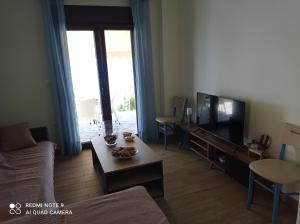 a living room with a couch and a tv at Sunset Apartment in Epanomi