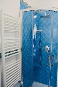 bagno con piastrelle blu e doccia in vetro di Rifugio Stellato a Conca dei Marini