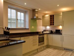 una cucina con armadi bianchi, lavandino e finestra di 4 Greenhaye Cottages - Uk31236 a Newnham