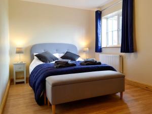 a bedroom with a bed with blue sheets and a window at 4 Greenhaye Cottages - Uk31236 in Newnham