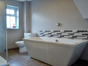 a white bath tub in a bathroom with a toilet at 4 Greenhaye Cottages - Uk31236 in Newnham
