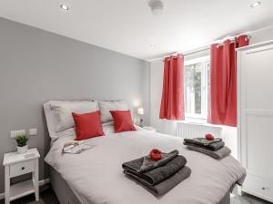 Una cama blanca con almohadas rojas y toallas. en Hill Crest Lodge 1 en Hemswell