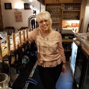 an older woman standing behind a counter in a wine shop at Jolly Sailor in Cawood