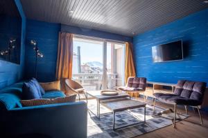 a blue room with a couch and chairs and a tv at Beautiful flat in L'Alpe d'Huez heart at the foot of the slopes - Welkeys in LʼHuez