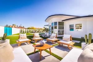 um pátio com cadeiras e mesas e uma casa em White Pearl - Pool - Spa - Mountain Views em Palm Springs