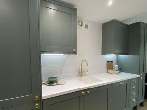 a kitchen with green cabinets and a sink at Oakleigh in Old Brampton