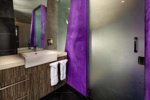 a purple bathroom with a sink and a mirror at The Moment Hotel in Los Angeles