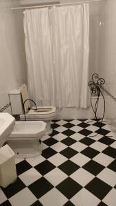 a bathroom with a toilet and a black and white checkered floor at Quinta da Barbosa in Folgosinho