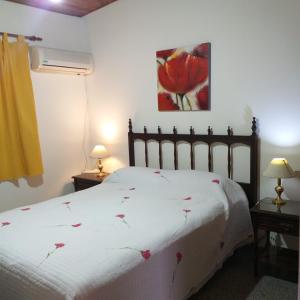 Un dormitorio con una cama blanca con flores rojas. en La casita en Paraná