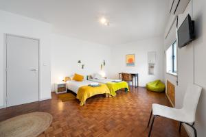 a bedroom with two beds and a tv in a room at Bordallo's Lodge in Caldas da Rainha