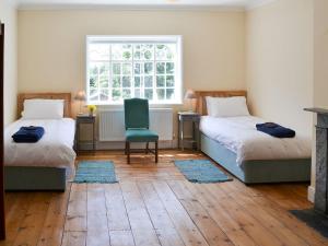 a room with two beds and a chair and a window at The Dower House 