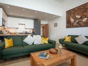 a living room with two green couches and a table at Bullens Rock in Ilfracombe