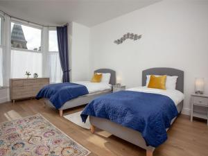 a bedroom with two beds with blue and yellow pillows at Bullens Rock in Ilfracombe