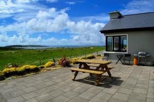 a picnic table on a patio with a view of the ocean at Cottage 103 - Claddaghduff in Cleggan