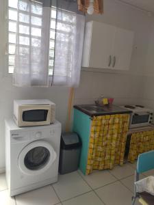 a kitchen with a washing machine and a microwave at studio sympa in Port-Louis
