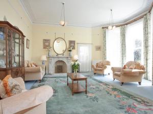 a living room with a fireplace and chairs and a mirror at Longcroft House in Torquay