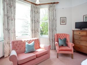 a living room with a pink couch and two chairs at Longcroft House in Torquay