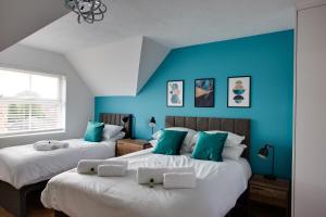 Duas camas num quarto com paredes azuis em ST AUSTELL - Spacious Home, High Speed Wi-Fi, Free Parking, Garden em Swindon