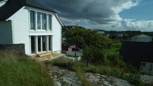 a white house with a porch and a wooden ramp at Apartment , Øygarden, Bergen in Torsteinsvik