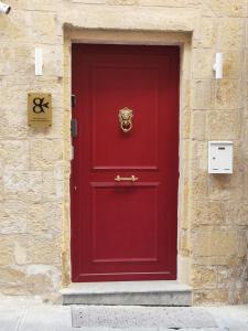 a red door with a gold lion on it at Valletta Home -Dar il-Kavallier Jacques de Quiqueran in Valletta