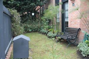 un banco del parque sentado en un patio junto a un edificio en Belmira House Cedritos, en Bogotá