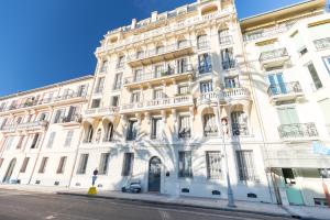 a large white building with a car parked in front of it at LE 323 PROM - 2 chambres - AC - PARKING - tram et supermarché proches - Front de mer in Nice