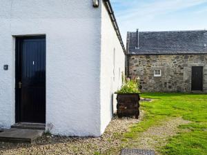a white house with a black door and a yard at Ferrycroft 1 - Uk33395 in Isle of Gigha