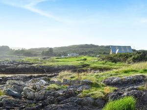 a field with rocks and a house in the background at Ferrycroft 1 - Uk33395 in Isle of Gigha