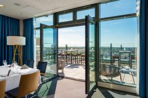 a dining room with a table and chairs and glass doors at Radisson Blu Hotel Rostock in Rostock