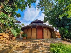 a small building with a thatched roof in a garden at Hotel Terra Barichara in Barichara