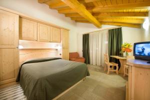 Schlafzimmer mit einem Bett, einem Schreibtisch und einem TV in der Unterkunft Boscone Suite Hotel in Madesimo