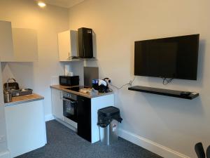 a room with a kitchen with a tv on the wall at Nelson st ALVA in Largs