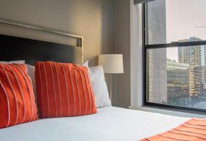 a bed with orange and white pillows and a window at Hotel Max in Seattle
