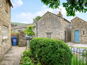 a stone house with a blue door and a fence at Holly Cottage in Kettlewell