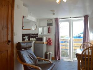 a kitchen with a chair and a table and a microwave at Paramount Cottage in Farden