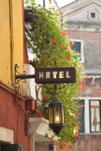 un letrero de la calle al lado de un edificio con flores en Hotel dalla Mora en Venecia