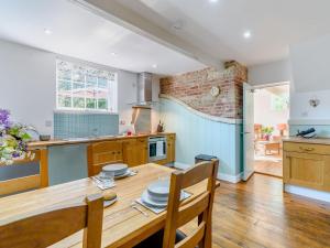 cocina con mesa de madera y pared de ladrillo en The Hideaway The Den en Sittingbourne