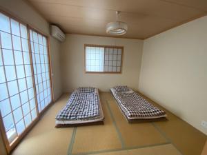 two beds in a room with two windows at 琵琶湖畔澄の宿 in Otsu