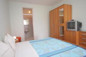 Schlafzimmer mit einem Bett und einem Schrank mit einem TV in der Unterkunft Double Room Medveja 7775a in Lovran