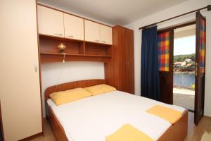a bedroom with a bed with wooden cabinets and a window at Apartments by the sea Basina, Hvar - 8749 in Vrbanj