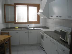 a kitchen with white cabinets and a sink and a microwave at Holiday homes Bonamar in Colònia de Sant Jordi